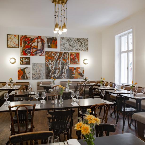 Ein Speisesaal mit gedeckten Tischen und Kunstwerken an den Wänden.