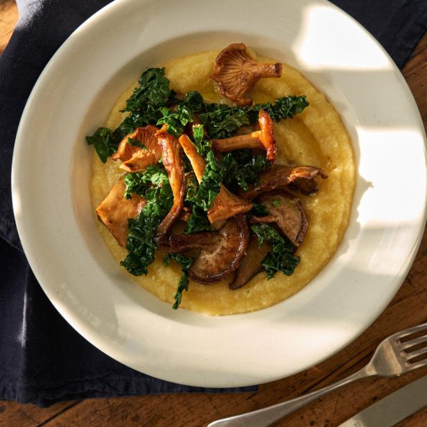 Polenta mit sautierten Pilzen und Grünkohl auf einem Teller.