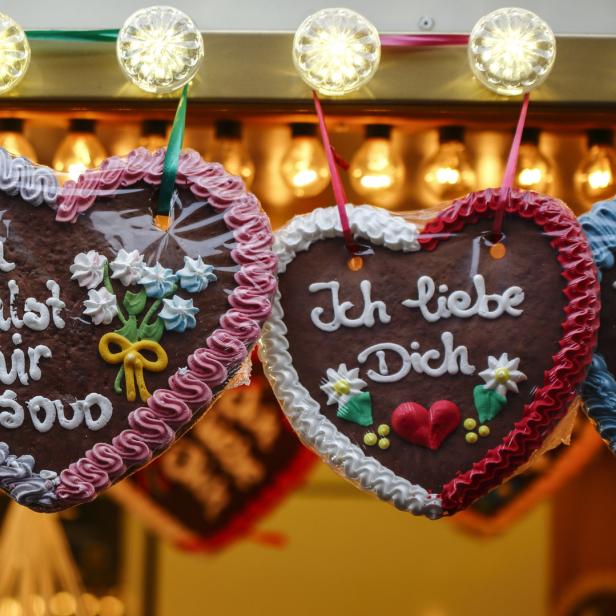 Lebkuchenherzen mit Aufschriften hängen auf einem Weihnachtsmarkt.