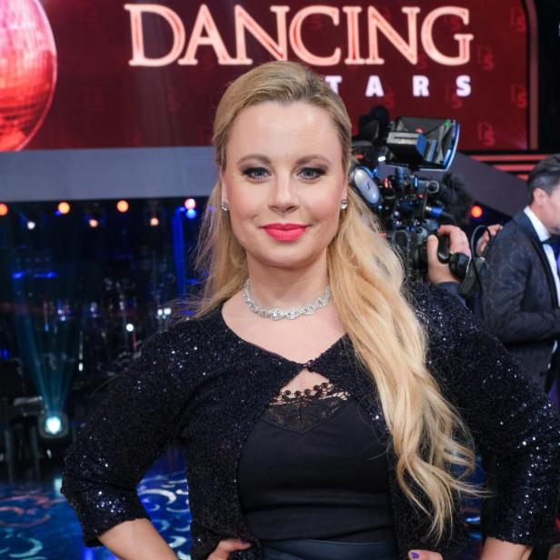 Eine Frau in Abendgarderobe posiert vor dem „Dancing Stars“-Logo.