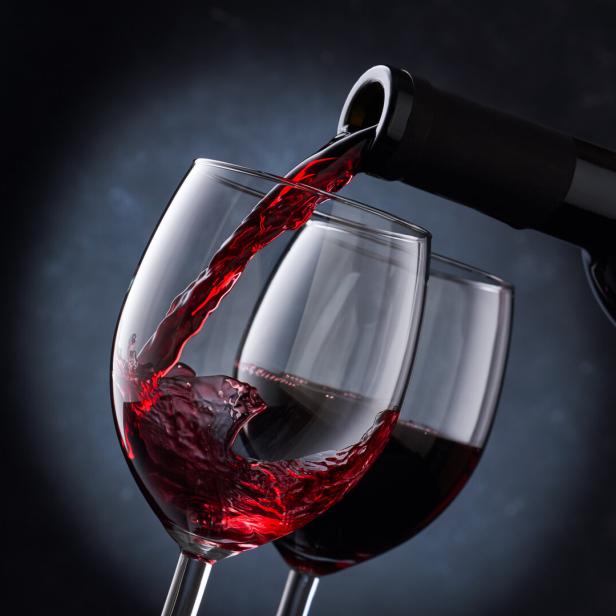 Rotwein wird in zwei Gläser eingeschenkt.