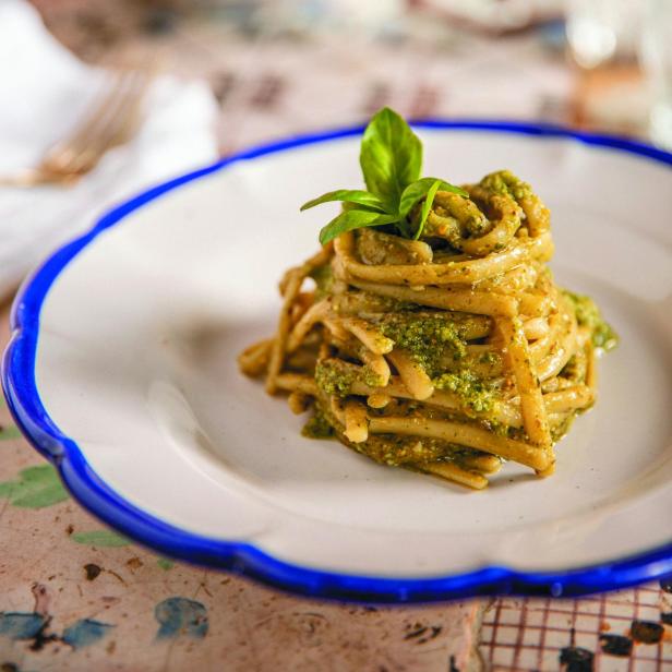 Ein Teller Pasta mit Pesto und Basilikum garniert.