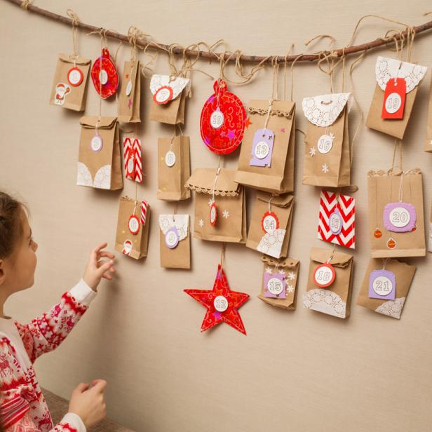 Ein Mädchen betrachtet einen selbstgemachten Adventskalender mit kleinen Geschenktüten.