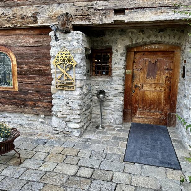 Eingang zum „Romantik Restaurant“ in einem Gebäude mit Stein- und Holzelementen.