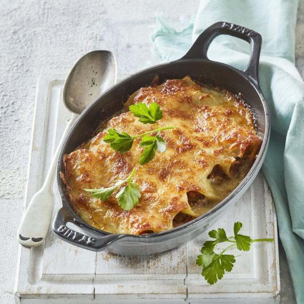 Cannelloni in einer schwarzen Auflaufform, garniert mit Petersilie.