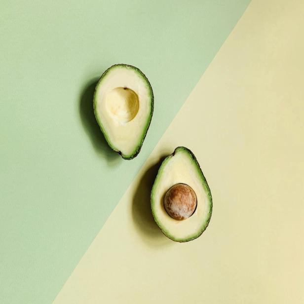 Zwei halbe Avocados liegen auf einem zweifarbigen Hintergrund.