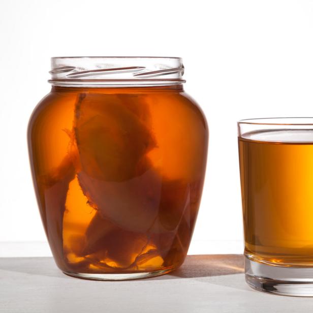Ein Glas und ein Glas mit Kombucha stehen auf einem Tisch.