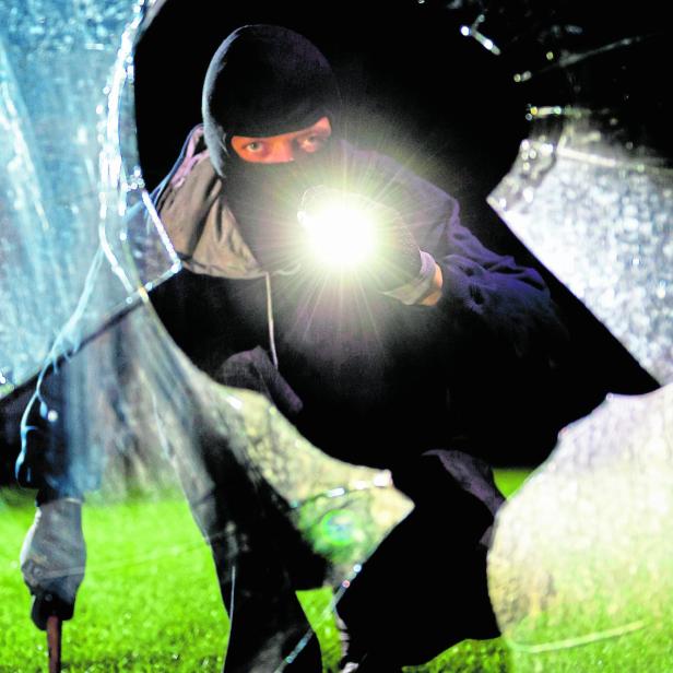 Maskierter Einbrecher mit Taschenlampe.
