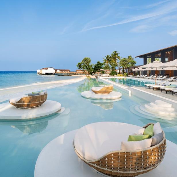 Ein Resort mit Liegen im Wasser und Blick auf das Meer.