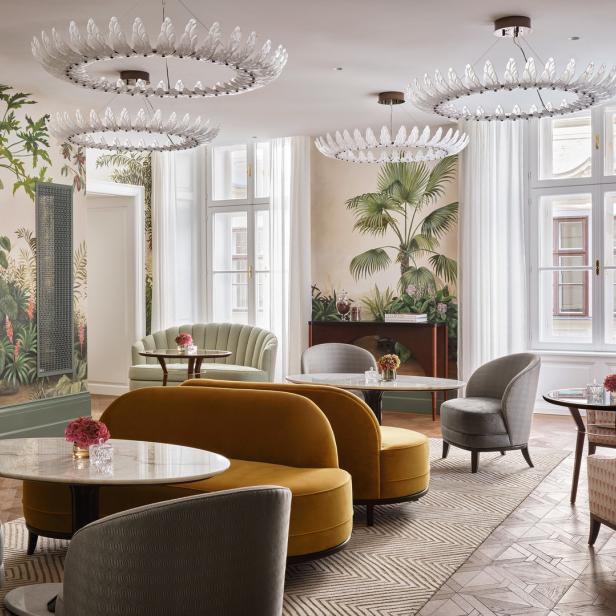 Ein elegant eingerichteter Raum mit floralen Wandmalereien, Sofas und Sesseln um kleine Tische.
