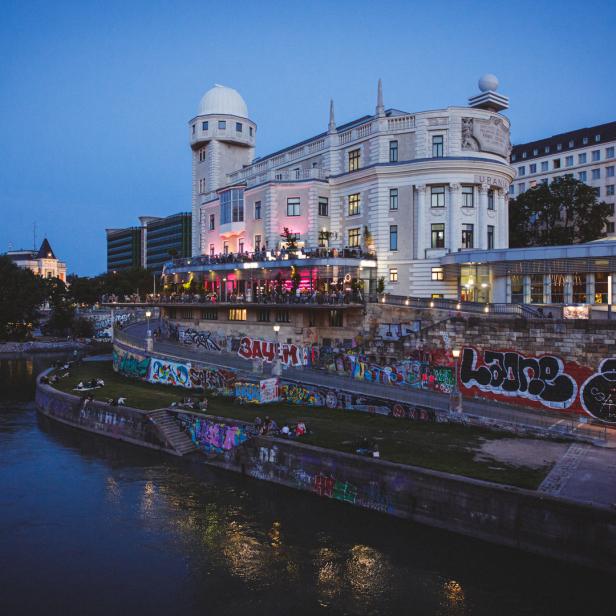Die Wiener Urania und der Donaukanal bei Dämmerung.