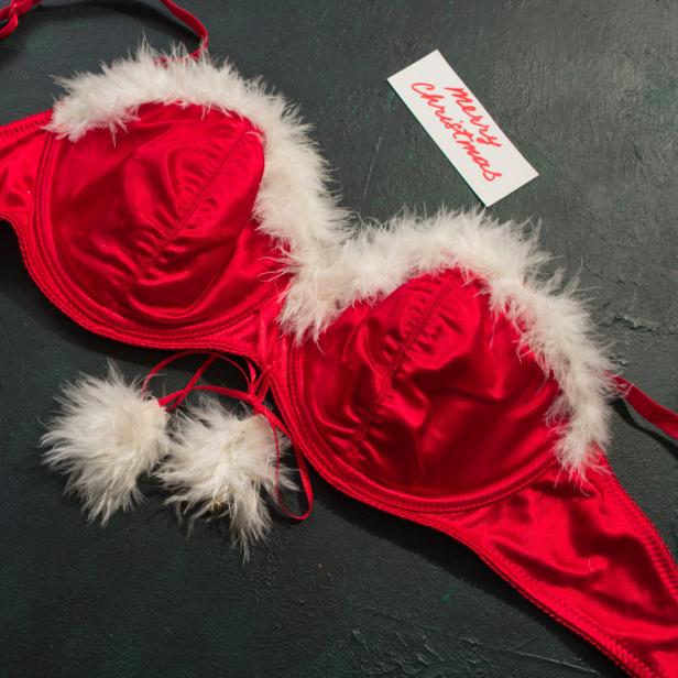 Ein roter BH mit weißem Fellbesatz liegt neben einer Weihnachtskarte.