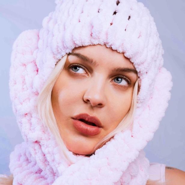 Die Sängerin Anne-Marie trägt eine flauschige, rosa Mütze und einen Schal.