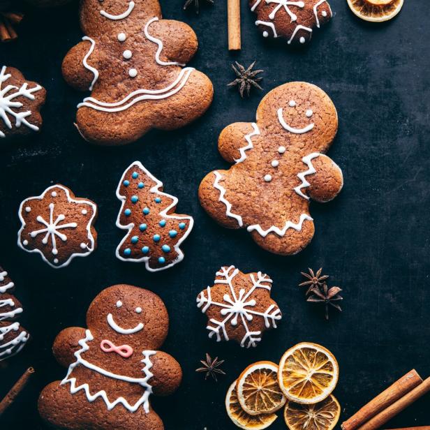 Lebkuchenmänner und andere weihnachtliche Kekse liegen auf einem dunklen Untergrund.