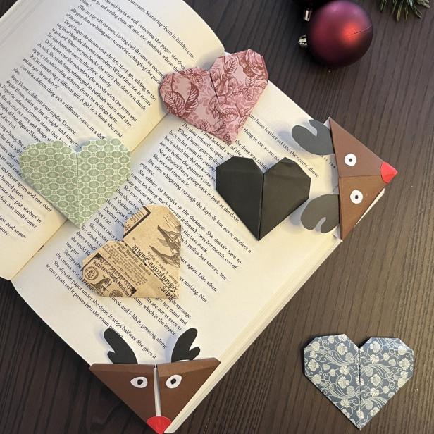 Ein aufgeschlagenes Buch mit Origami-Herzen und Rentier-Lesezeichen verziert.