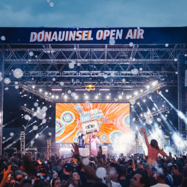 Eine Menschenmenge genießt das Donauinselfest Open Air mit einer Bühne im Hintergrund.