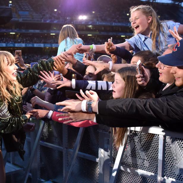 Taylor Swift interagiert während eines Konzerts mit Fans an der Absperrung.