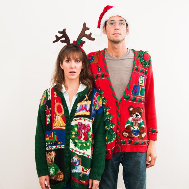 Ein Paar trägt Weihnachtspullover und Stirnbänder mit Weihnachtsmotiven.