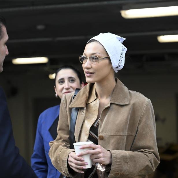 Bella Hadid hält einen Kaffeebecher in der Hand und spricht mit einem Mann.