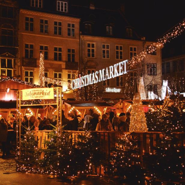 Ein belebter Weihnachtsmarkt mit Lichtern und Menschen in der Nacht.