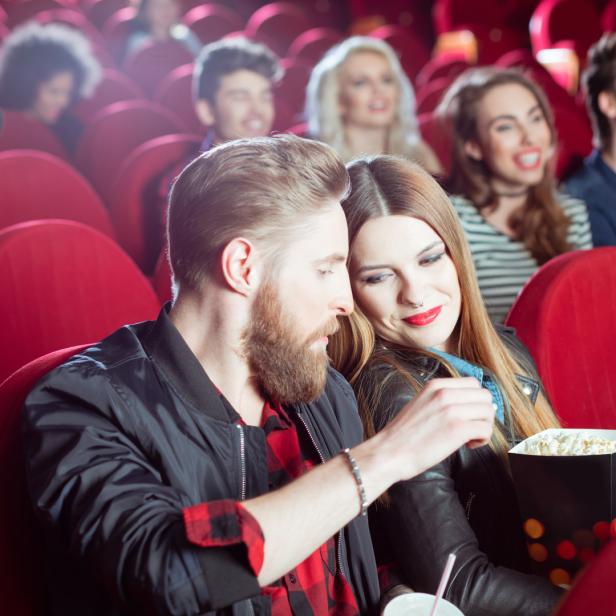 Ein Paar teilt sich Popcorn im Kinosaal.