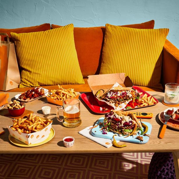 Ein Tisch ist mit verschiedenen Speisen wie Döner, Pommes und Currywurst gedeckt.