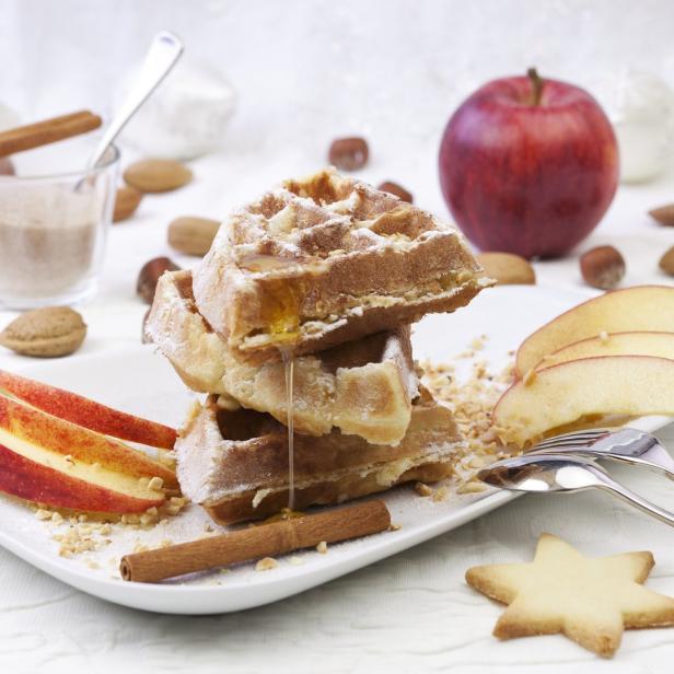 Ein Teller mit Waffeln, Apfelspalten, Zimtstangen und einem Sternförmigen Keks.