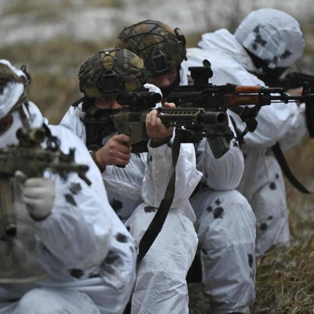 Eine Gruppe Soldaten in Tarnanzügen zielt mit Gewehren.