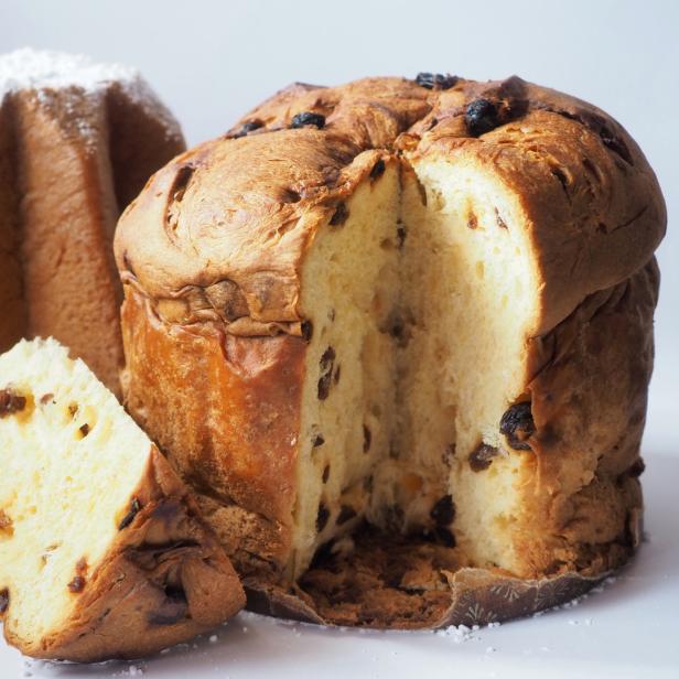 Ein angeschnittener Panettone mit Rosinen und ein Pandoro mit Puderzucker.