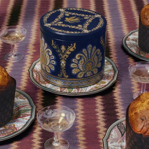 Ein Arrangement aus Panettone, Sektgläsern und einer verzierten Dose auf einem Tisch.