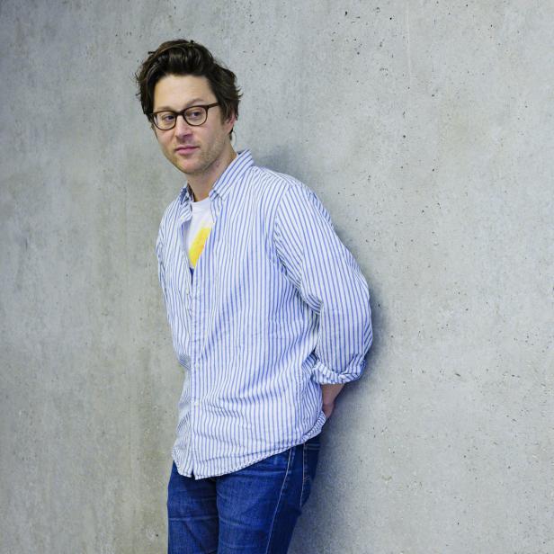 Arthur Arbesser lehnt an einer grauen Wand.