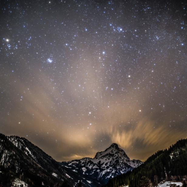 Sternenhimmel über einer verschneiten Berglandschaft.