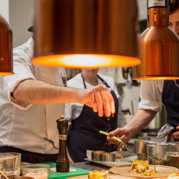 Ein Koch garniert Speisen in einer Restaurantküche.
