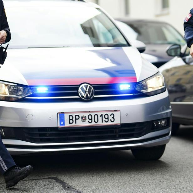 Zwei Polizisten stehen neben einem Streifenwagen.