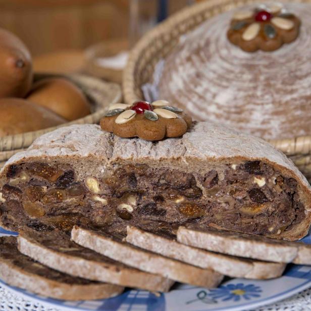 Ein angeschnittenes Kletzenbrot mit Feigen und Nüssen auf einem Teller.