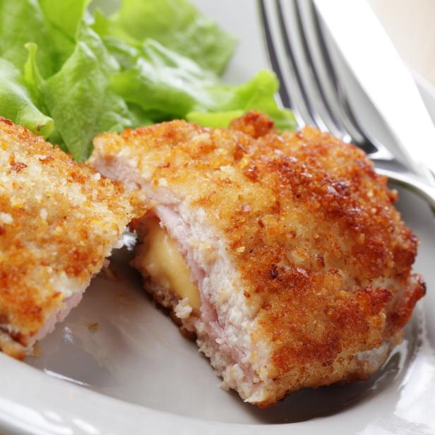 Cordon bleu mit schmelzendem Käse und Schinken auf einem Teller mit Salat.