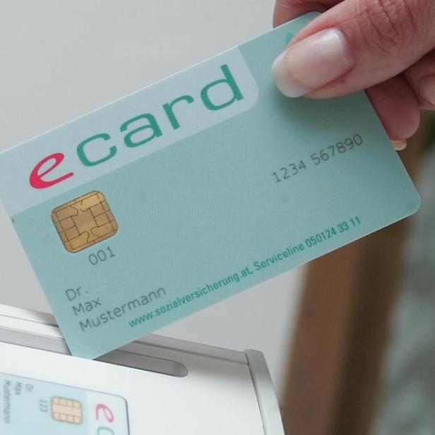 Eine Hand führt eine E-Card in ein Lesegerät ein.