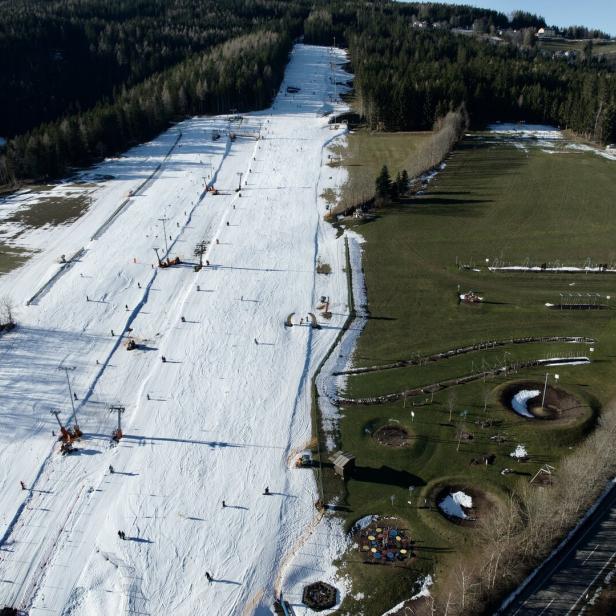 „Wexl-Spiel“ der Jahreszeiten. Links fahren Kinder Ski, rechts daneben wird im Motorikpark geklettert.