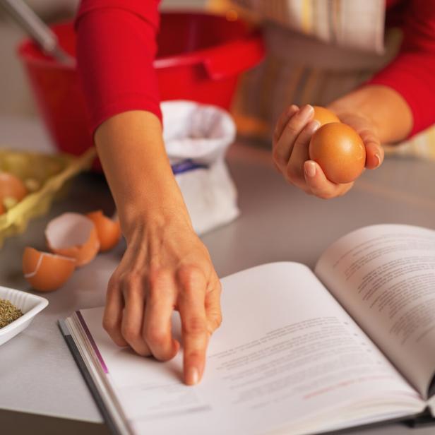 Eine Person liest ein Rezept und hält Eier in der Hand.