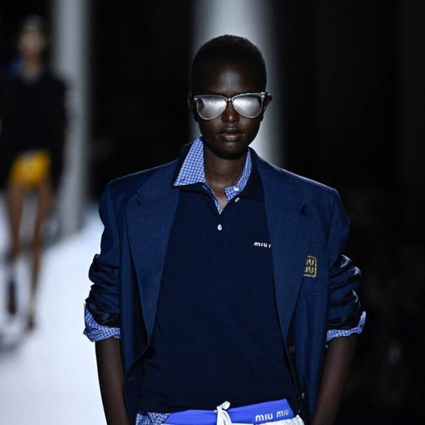 Ein Model präsentiert einen Preppy-Look mit Blazer, Poloshirt und Rüschenrock.