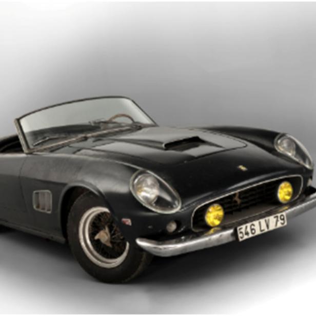 Ein schwarzer Ferrari 250 GT California Spider steht vor einem grauen Hintergrund.