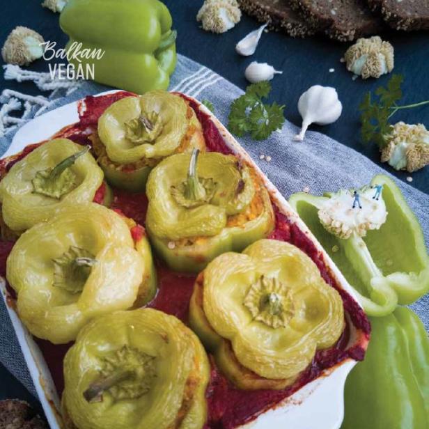 Gefüllte grüne Paprika in einer Auflaufform, garniert mit Knoblauch und Brot.
