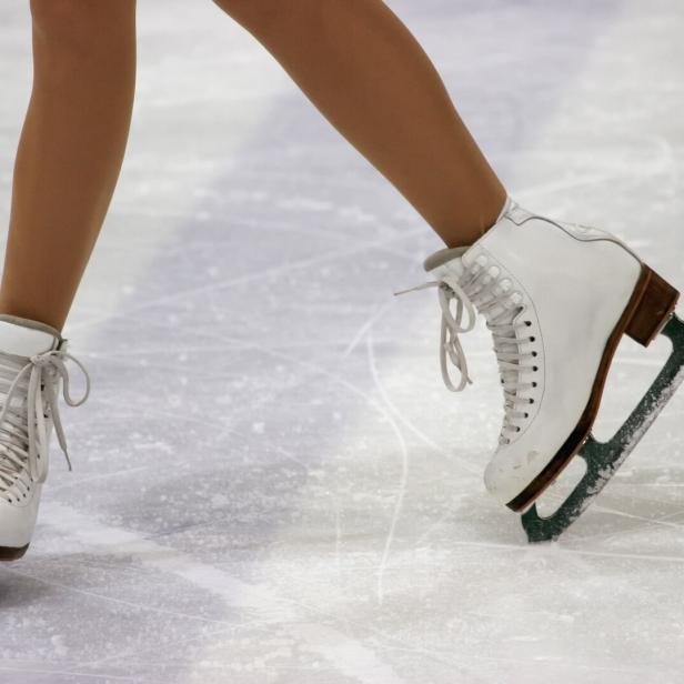 Nahaufnahme von weißen Schlittschuhen auf einer Eisfläche.
