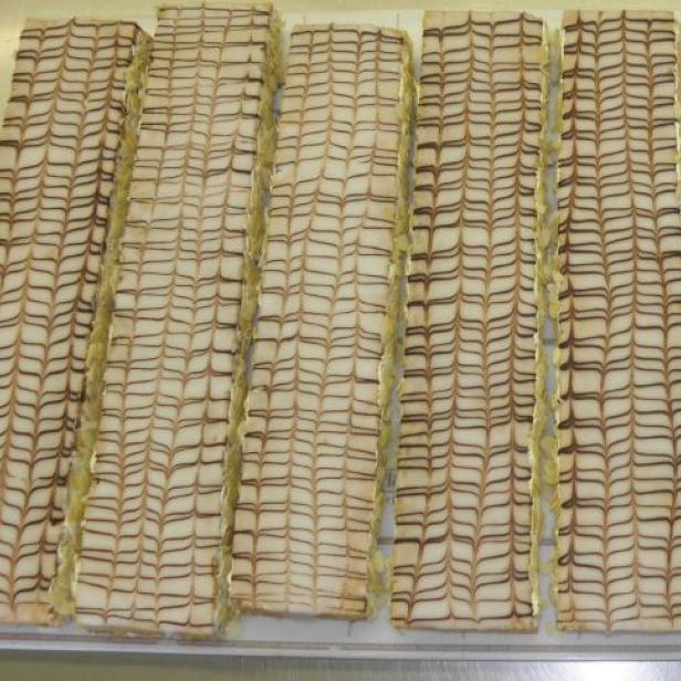 Mehrere rechteckige Cremeschnitten mit einem Muster aus Schokolade und Zuckerguss.