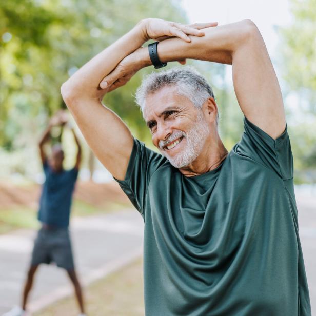 Älterer Mann macht Dehnübungen beim Joggen im Freien.