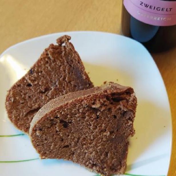 Zwei Stücke Schokoladenkuchen auf einem Teller, daneben eine Flasche Zweigelt.
