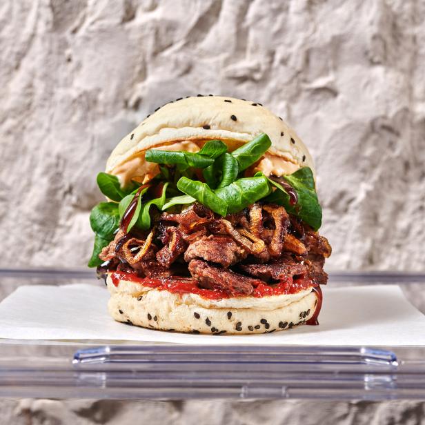 Burger mit Rindfleisch, Röstzwiebeln und Feldsalat auf einem Tisch.