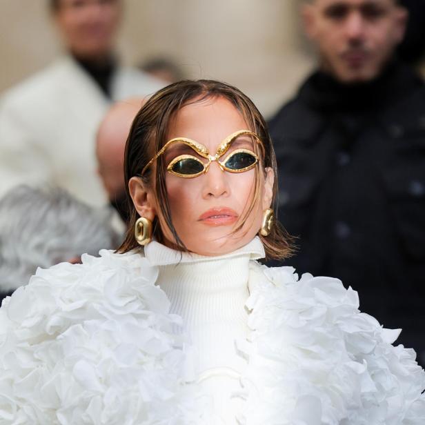 Jennifer Lopez trägt eine extravagante weiße Jacke und goldene Sonnenbrille.