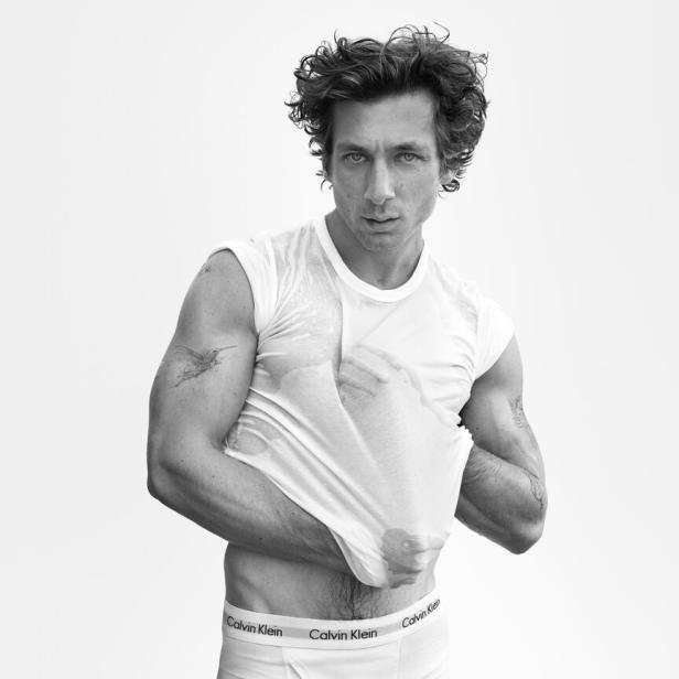 Ein Mann in Calvin Klein Unterwäsche zieht ein nasses T-Shirt aus.