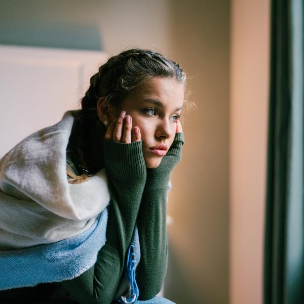 Mädchen sitzt auf dem Bett, enttäuscht und traurig.